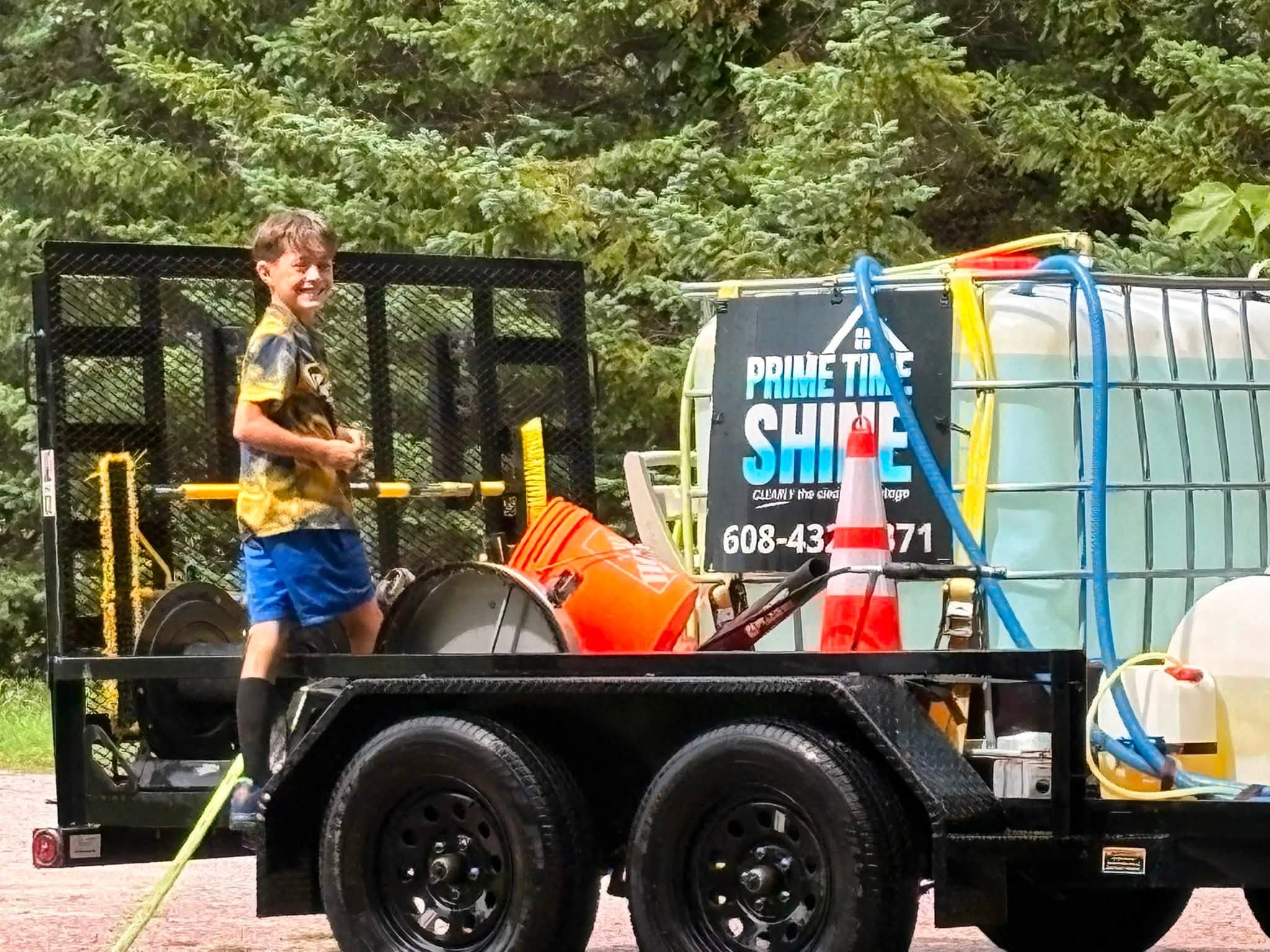 A young member of the Prime Time Shine family beside the branded equipment trailer