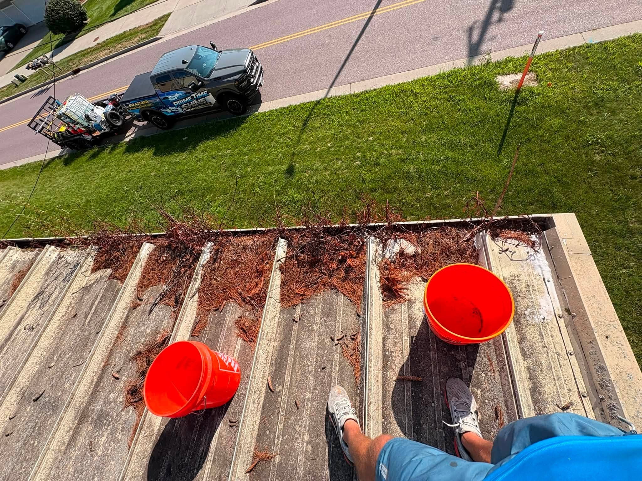 Roof debris and collection buckets above a Prime Time Shine work truck