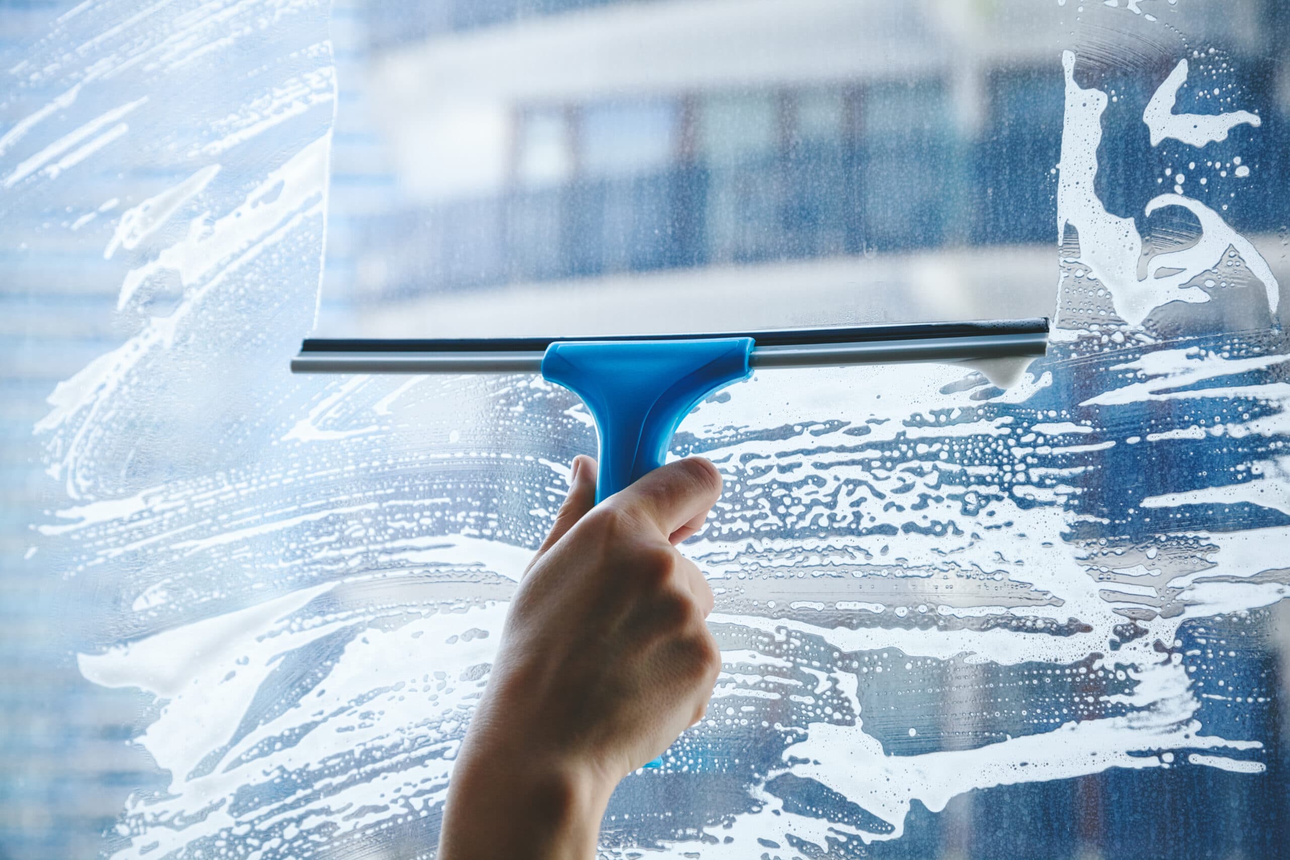 Window glass being cleaned with soap and a squeegee